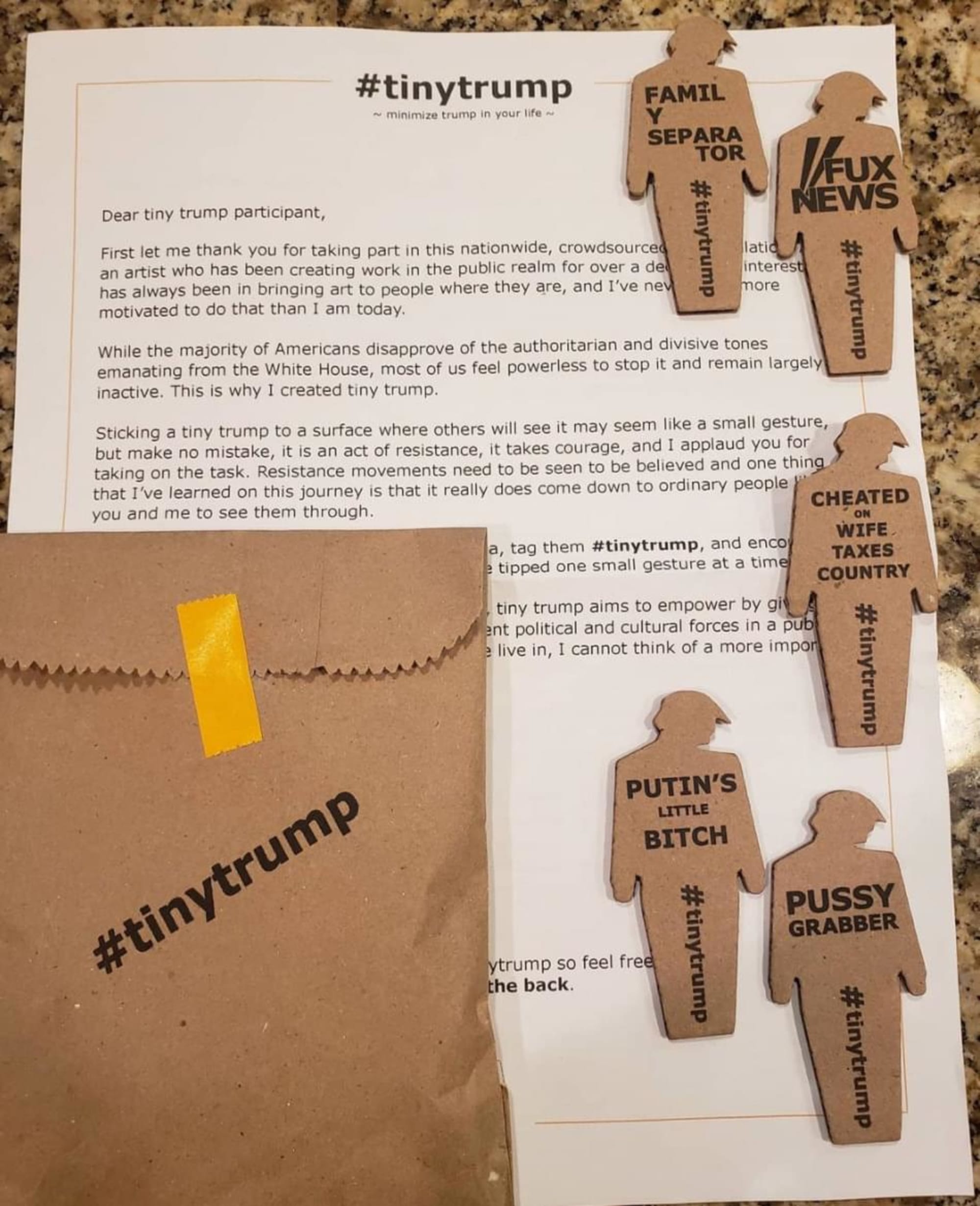 an unboxing photo of five tiny trumps positioned on top of the participant welcome letter and next to the paper brown bag pouch stamped 'tiny trump' that they came in