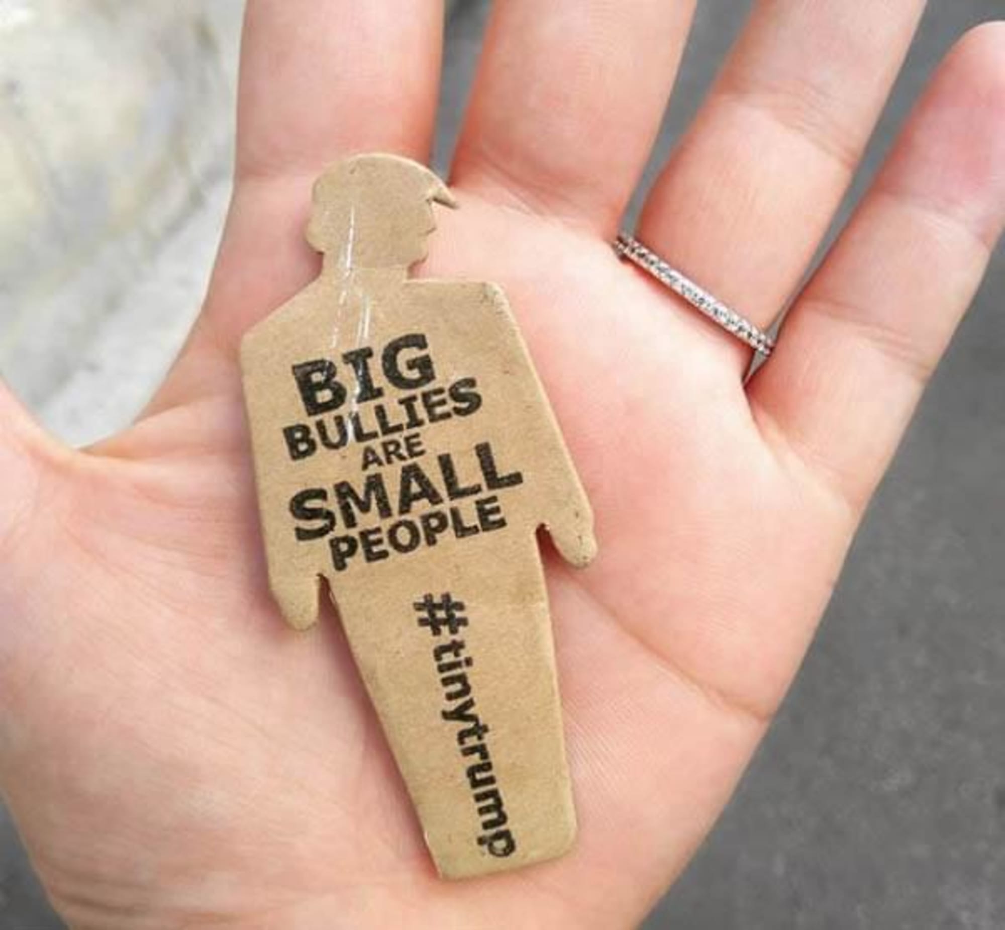 a photograph of a tiny trump in the palm of someone's hand